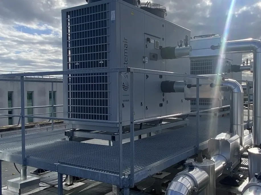 Groupe de production en toiture-terrasse : caisson métallique, batteries à ailettes, passerelle et garde-corps galvanisés, tuyauteries calorifugées en acier inoxydable.